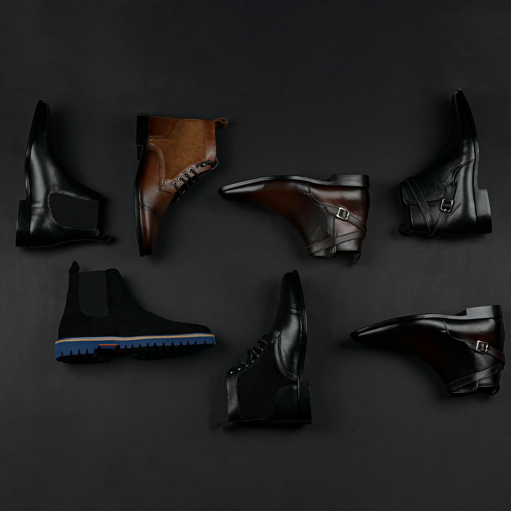 Stylish men's leather shoes arranged on a black background, showcasing various styles.